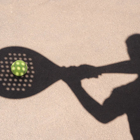 Shadow of a person holding a paddle, ready to hit a padel ball on a sunlit court, during the 60-Min Private Lesson w/ Dani by Padel Smash.