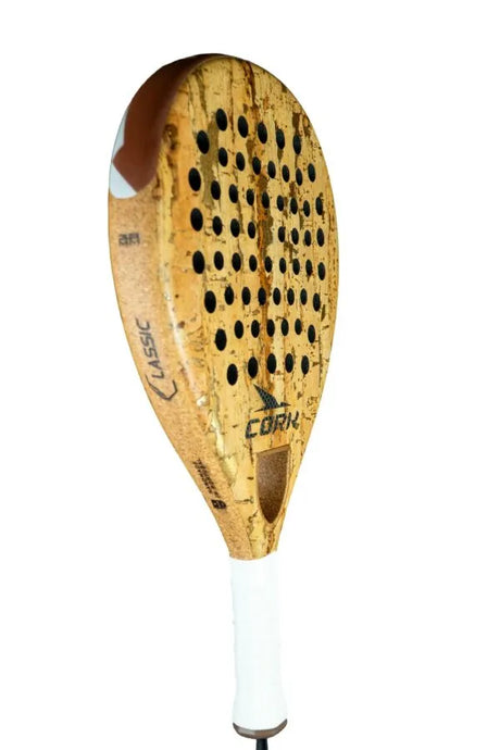 Introducing the Cork Padel Classic by Cork Padel: A sleek racket with a cork surface, innovative drilling pattern, white handle, and black brand markings on its wooden texture—designed for comfort and control with every swing.