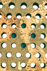 The Cork Padel Extreme Green by Cork Padel features a camouflage-like textured surface with earthy green and beige tones, characterized by multiple rows of round holes, each revealing a dark interior, reminiscent of a limited edition racket.
