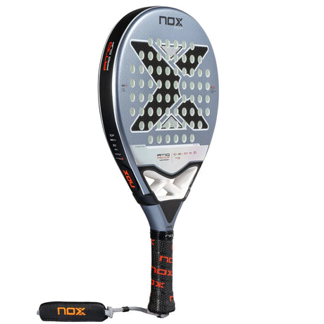 The Nox Padel Racket AT Pro Cup Comfort 25 by Agustín Tapia features a bold X on its face and Fiber Glass Silver technology. It has a black handle with branded grip, and its frame seamlessly blends grey and black shades for an unparalleled playing experience.