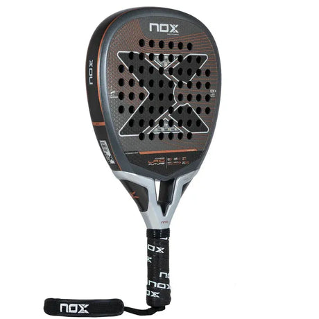 The NOX Padel Racket LA10 Future 2024 Leo Augsburger features a sleek design with a large X and perforations on its black and orange face. Made from aluminized 12K carbon fiber for enhanced power, it includes a black grip with NOX branding and a strap at the handles end for security.