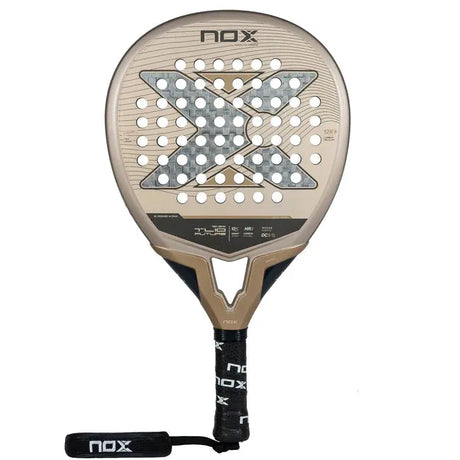 The NOX Padel Racket TL10 Future 2024 Tino Libaak boasts a gold and black teardrop shape with a perforated face, showcasing the brands signature X design. Its black handle features white branding and an attached wrist strap for versatile gameplay.